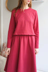 Person wearing a red outfit standing against a white wall.