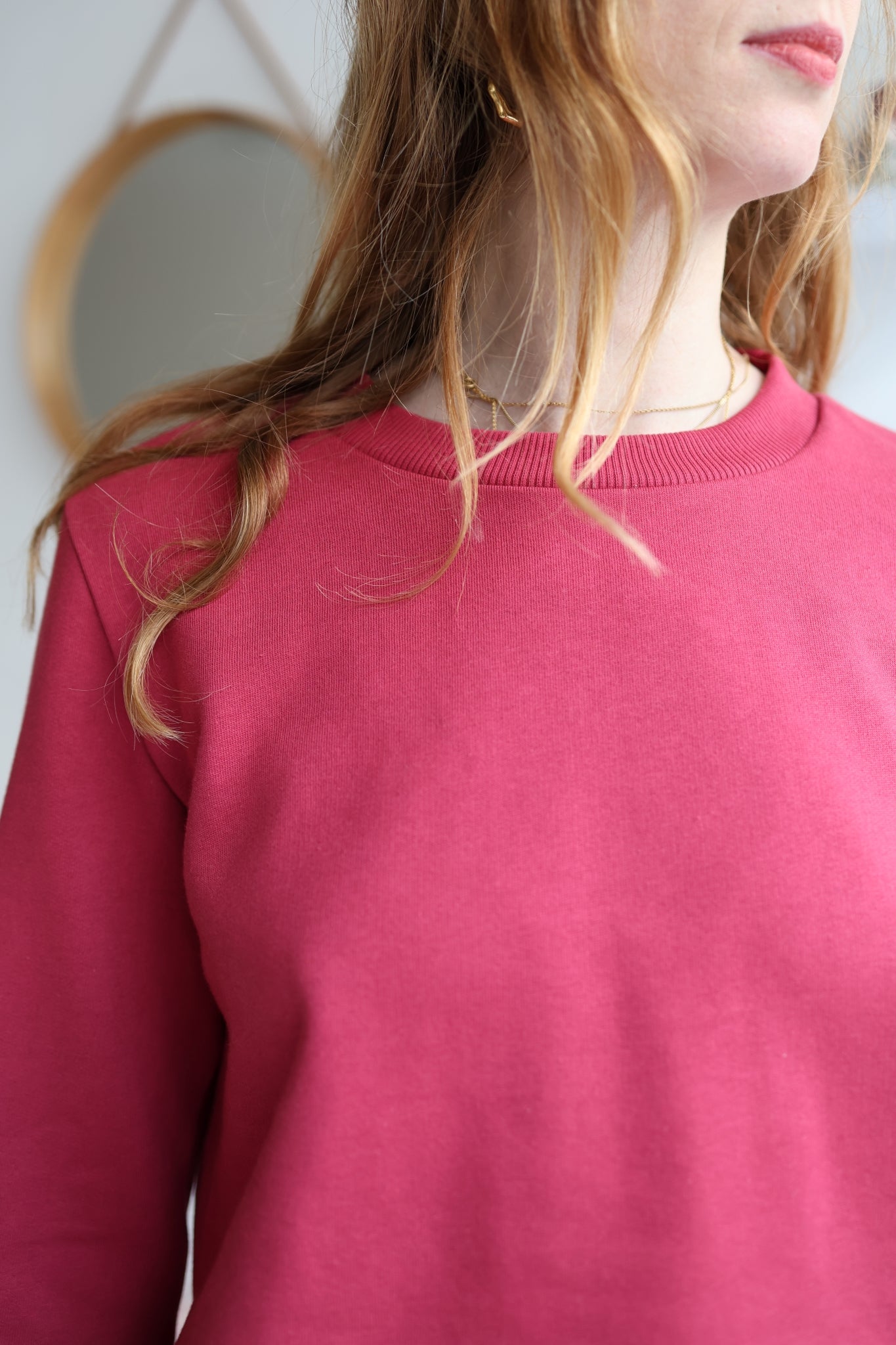 Person wearing a pink sweater with a blurred background