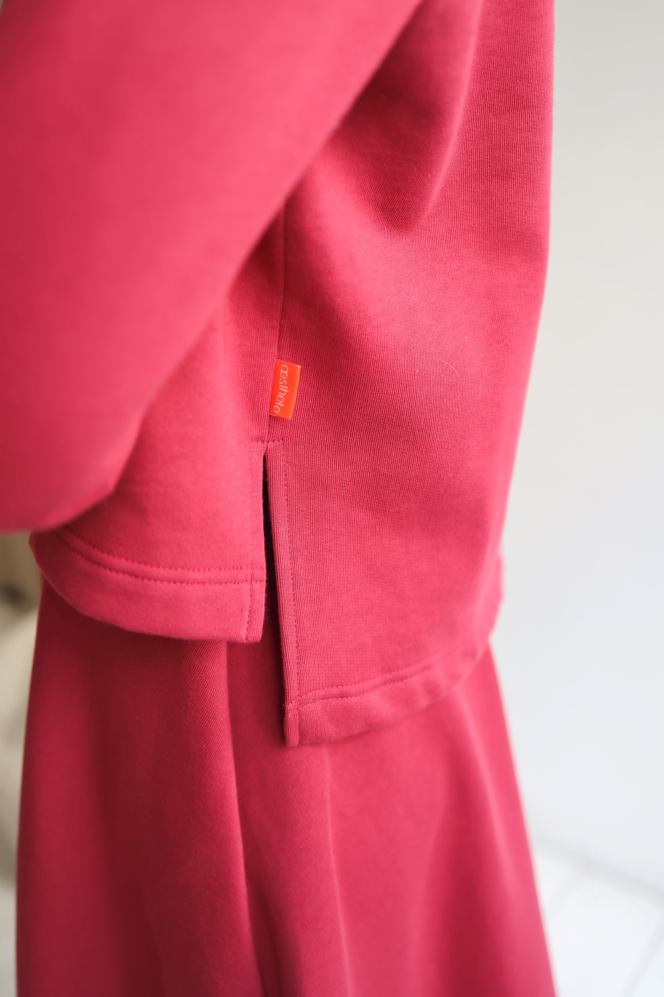 Close-up of a red sweatshirt with a brand tag on a white background